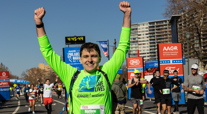 Matthew Cleaveland, a Penn Engineering doctoral student, raises his hands in triumph after completing the Philadelphia Marathon.