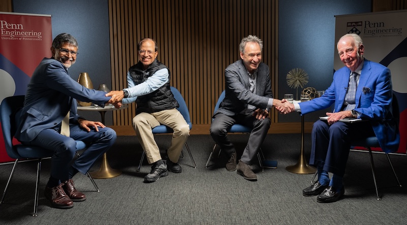 Vijay Kumar, Nemirovsky Family Dean of Penn Engineering, shakes hands with Rajendra Singh, Board member, at left, while Harlan Stone and Fred Warren, two other Board members, shake hands at right. All are seated and dressed in professional attire. 
